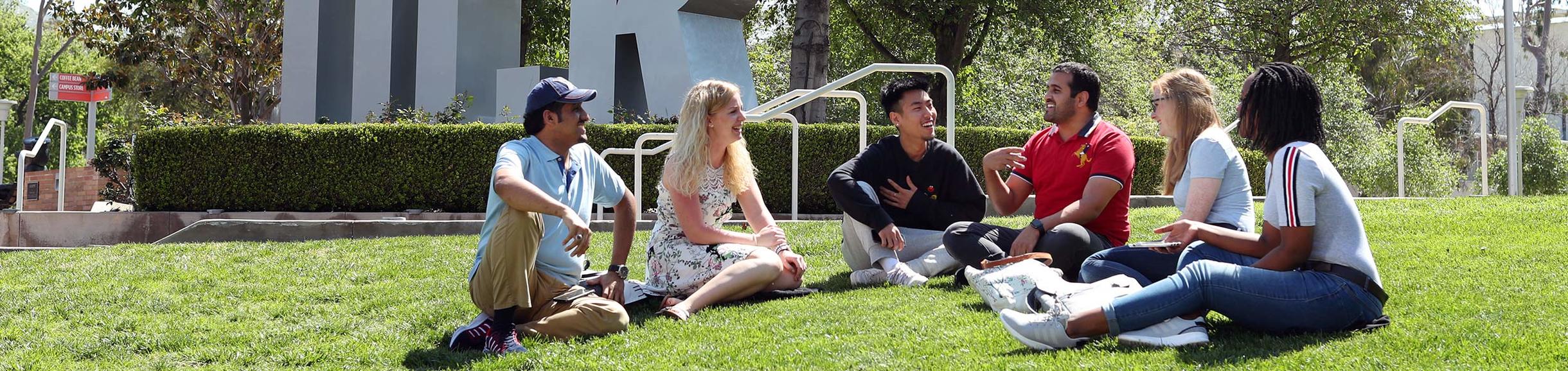 Students gather on a lawn with the UCR monument in the background